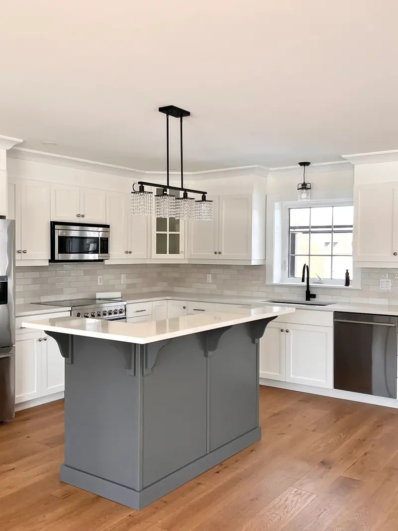 A finished kitchen with white cabinets and a grey island