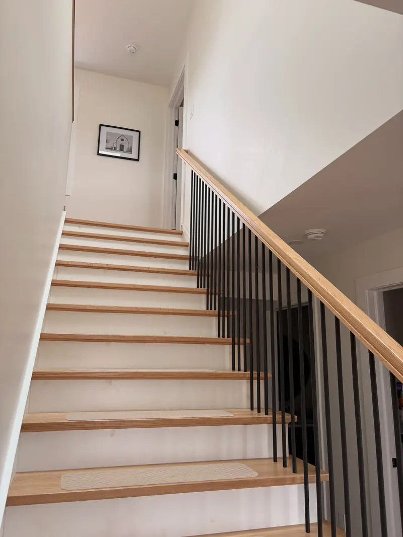 A finished staircase with a black metal railing