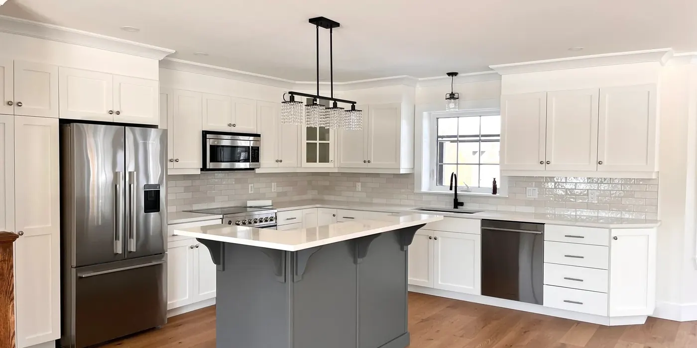 A finished kitchen with white cabinets and a grey island, built by IWR Renovations